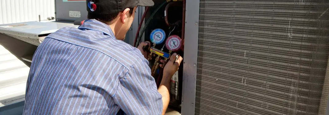 HVAC technician servicing a condenser unit in San Juan